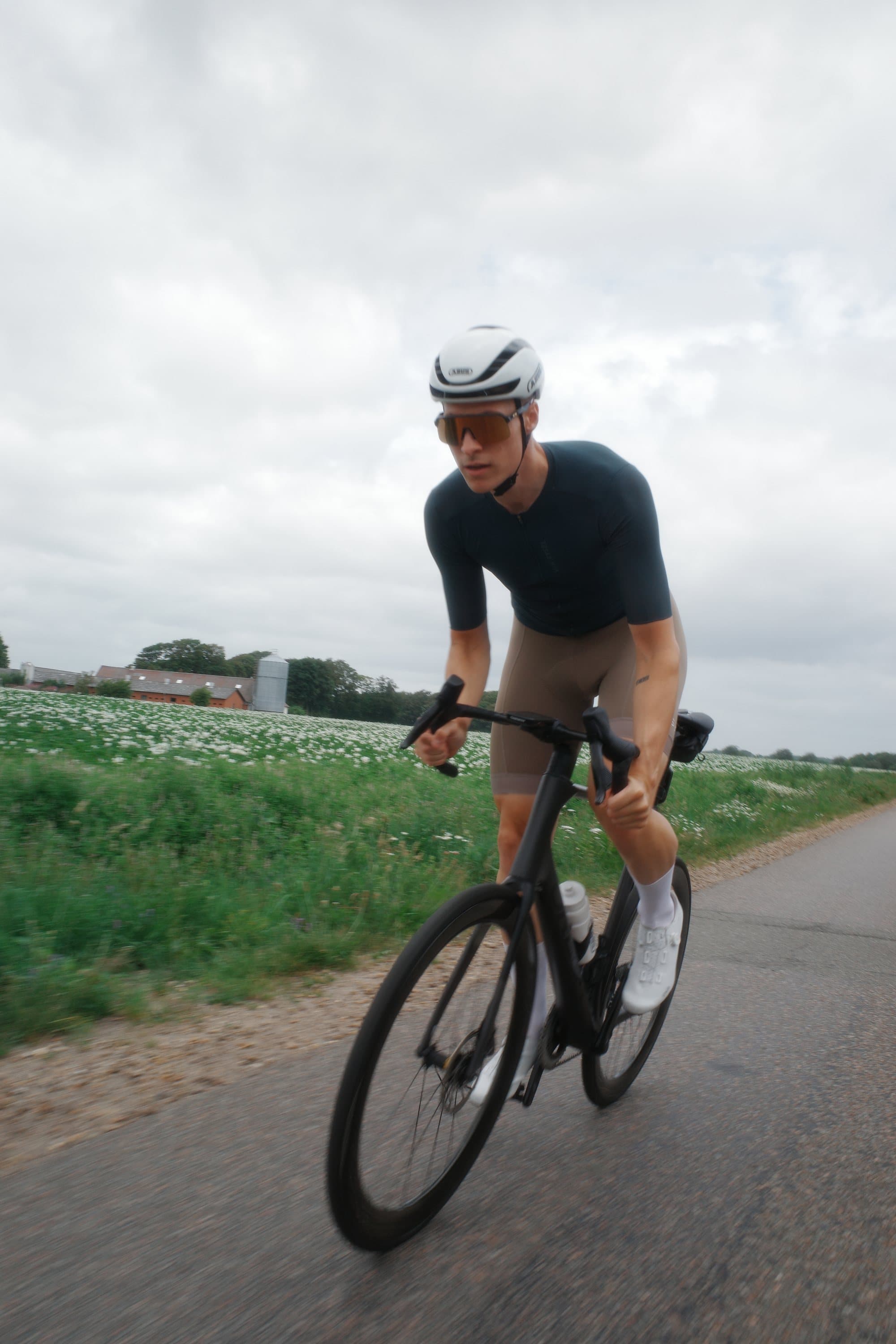 Cykeltræning på landevejen forbi marker under en grå himmel